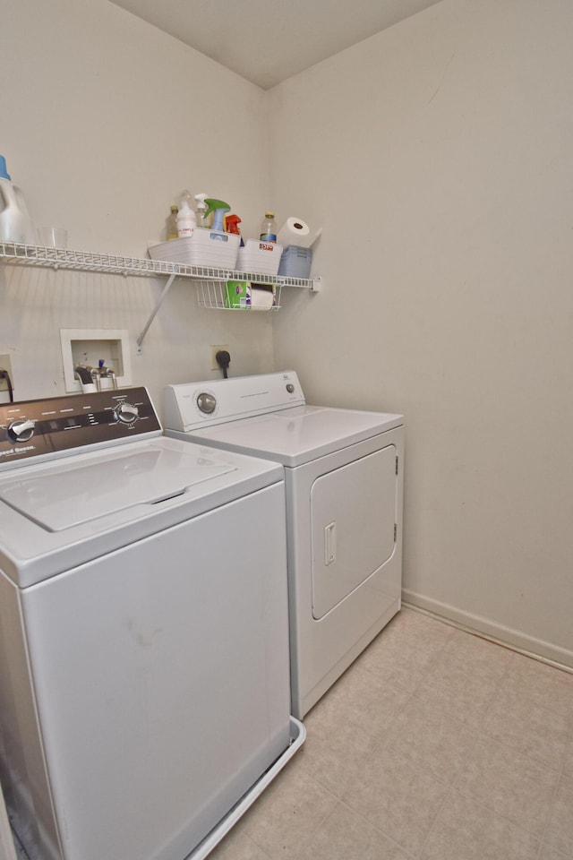 clothes washing area with light floors, washing machine and dryer, and laundry area