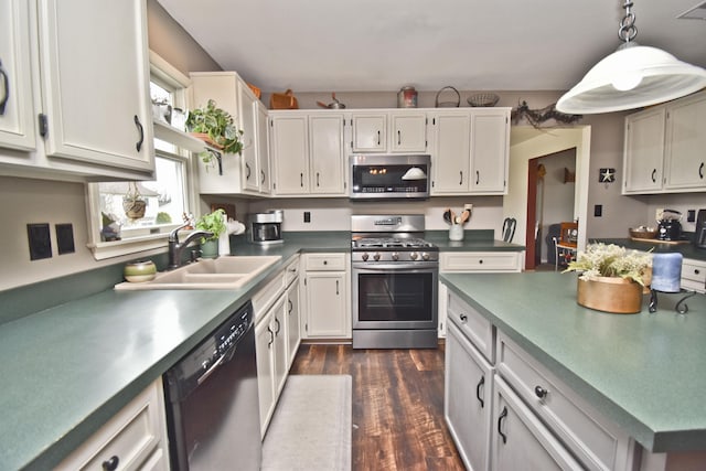 kitchen featuring pendant lighting, a sink, dark wood-type flooring, stainless steel appliances, and white cabinets