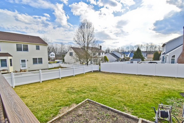 view of yard with fence, a residential view, and a garden