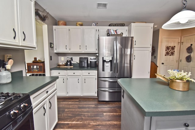 kitchen featuring dark wood-style flooring, visible vents, white cabinetry, stainless steel fridge, and dark countertops