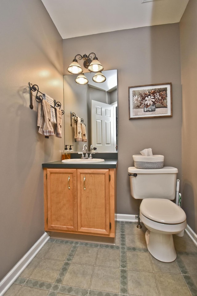 half bathroom featuring baseboards, tile patterned flooring, vanity, and toilet
