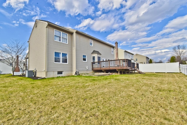 rear view of property with a yard, central AC unit, a wooden deck, and fence