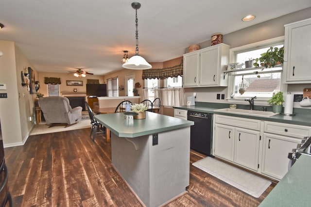kitchen with black dishwasher, ceiling fan, a sink, a kitchen island, and white cabinets
