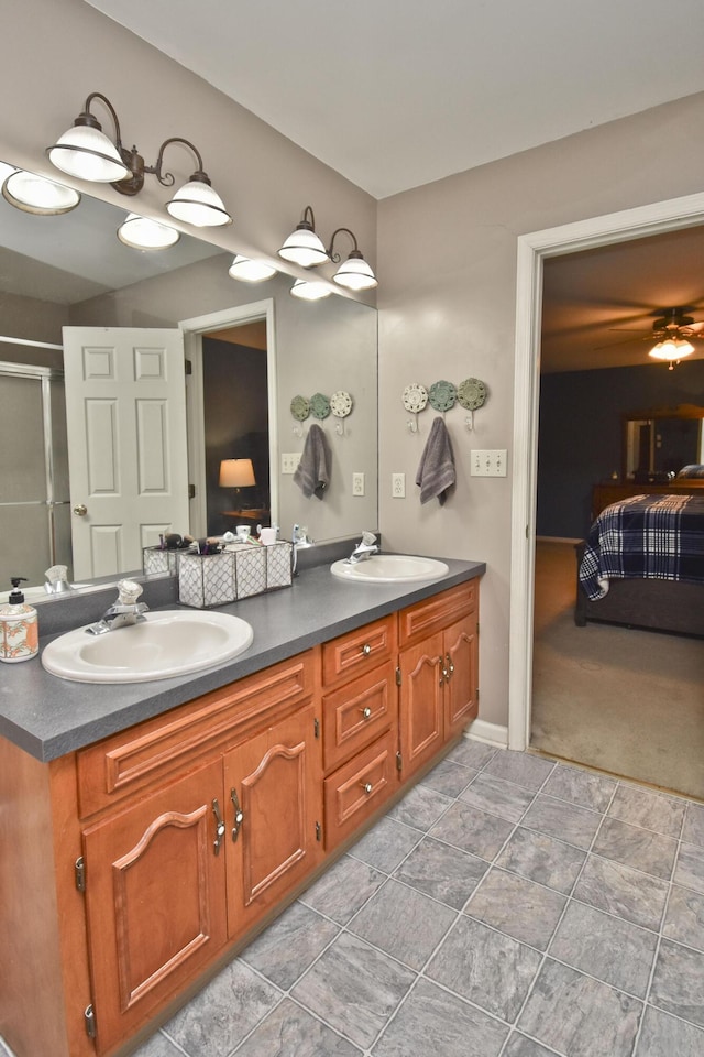 ensuite bathroom featuring double vanity, connected bathroom, a shower with door, and a sink