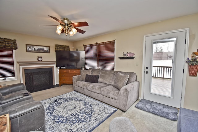 living room with a fireplace, ceiling fan, and light carpet