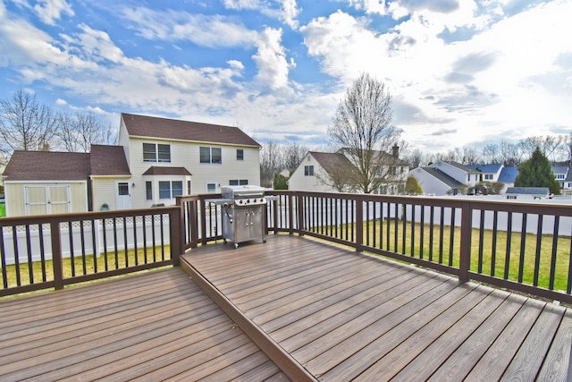 wooden terrace featuring area for grilling, an outbuilding, a residential view, and a lawn