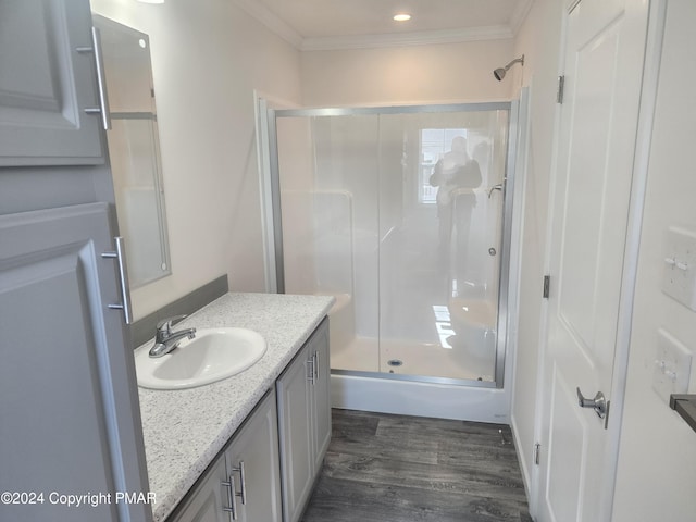 full bath featuring a shower stall, wood finished floors, vanity, and ornamental molding