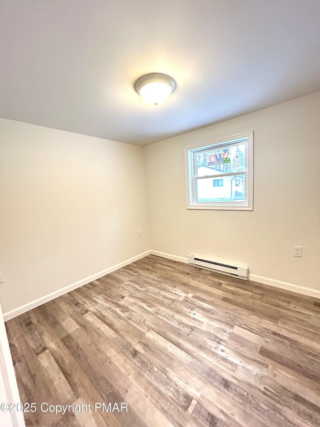 unfurnished room featuring baseboard heating and hardwood / wood-style flooring