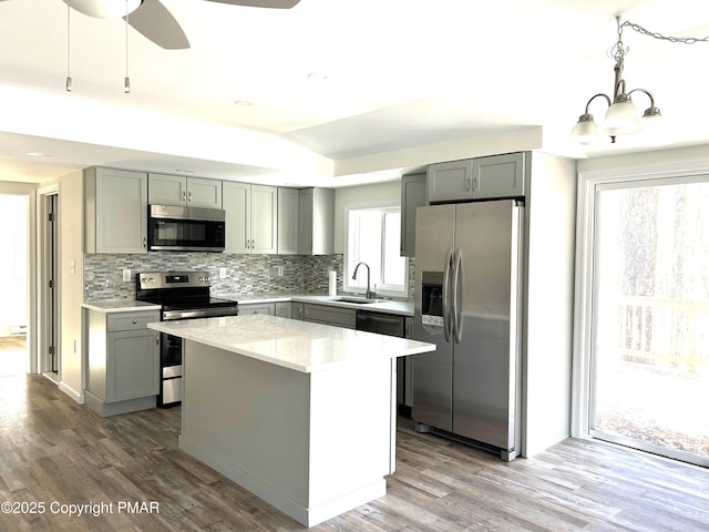 kitchen with tasteful backsplash, appliances with stainless steel finishes, wood finished floors, and gray cabinetry