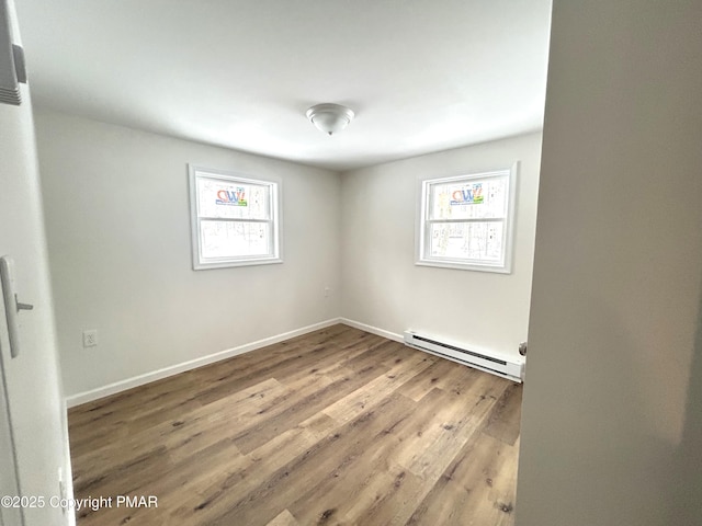 unfurnished room with baseboards, baseboard heating, and wood finished floors