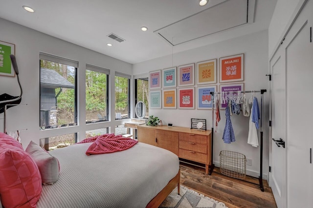 bedroom with recessed lighting, visible vents, wood finished floors, and attic access