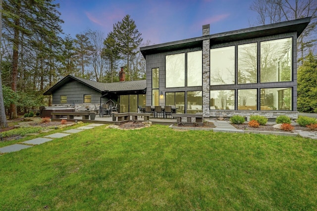 back of property featuring a lawn, a patio, and a chimney