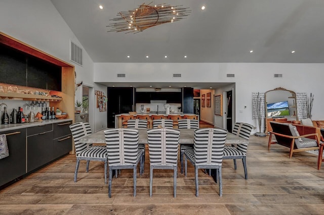 kitchen featuring dark cabinets, light wood-style floors, visible vents, and high vaulted ceiling