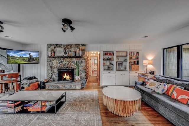living room with a fireplace, wood finished floors, and visible vents