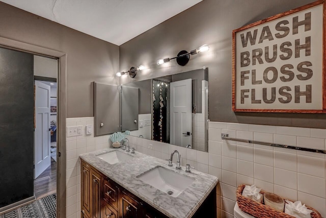 bathroom with a sink, tile walls, a wainscoted wall, and double vanity