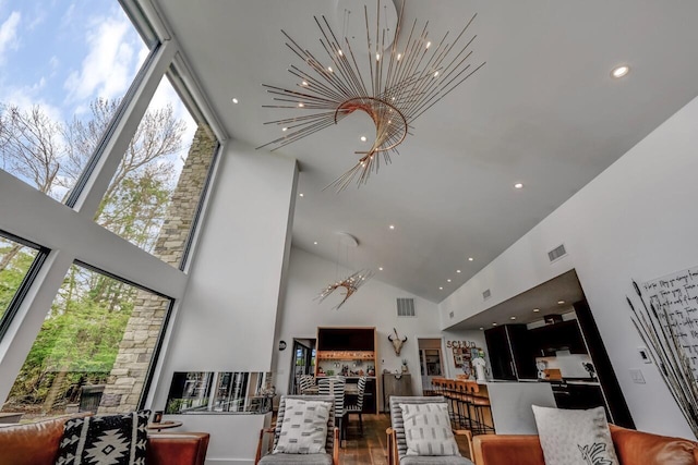 living area with visible vents, wood finished floors, high vaulted ceiling, a chandelier, and recessed lighting