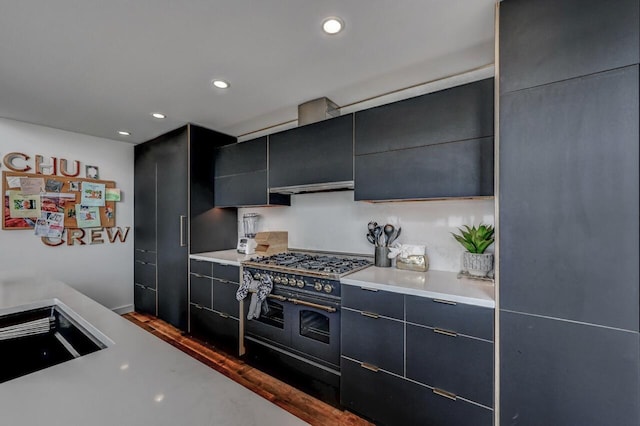 kitchen featuring recessed lighting, light countertops, range with two ovens, dark cabinets, and dark wood finished floors