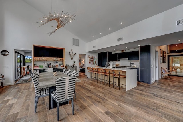dining room with a notable chandelier, high vaulted ceiling, visible vents, and light wood-type flooring