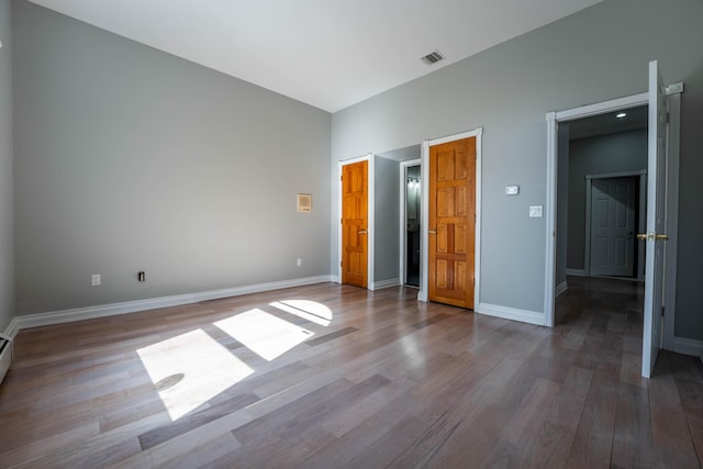 unfurnished bedroom featuring baseboards, wood finished floors, and visible vents