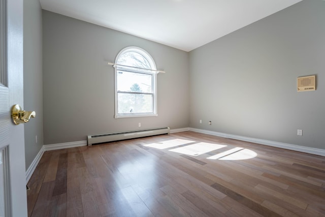 empty room with baseboards, a baseboard radiator, and wood finished floors