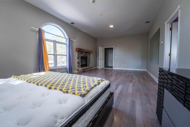 bedroom featuring visible vents, baseboards, wood finished floors, and a fireplace