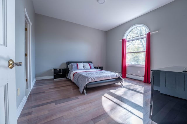 bedroom featuring baseboards, a baseboard radiator, and wood finished floors