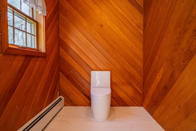 interior space with a baseboard radiator, wooden walls, and toilet