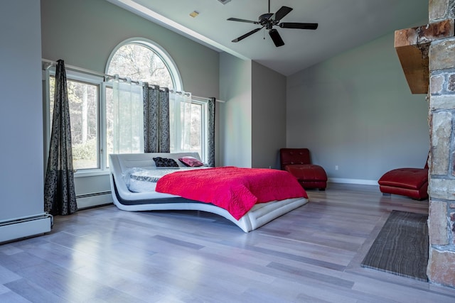 bedroom with a baseboard heating unit, multiple windows, and wood finished floors