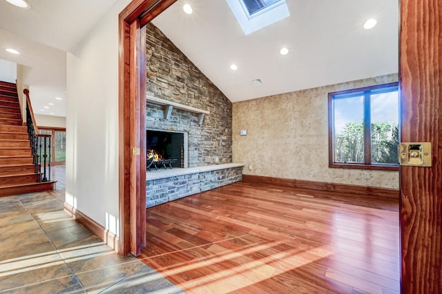 374 Packer Dr, Weatherly, PA 18255 - unfurnished living room featuring vaulted ceiling with skylight, a stone fireplace, wood finished floors, stairs, and baseboards