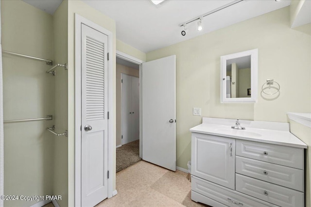 bathroom featuring rail lighting, vanity, and baseboards