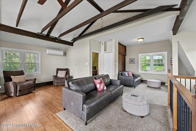 living room featuring vaulted ceiling with beams, light wood finished floors, baseboards, and a wall mounted air conditioner