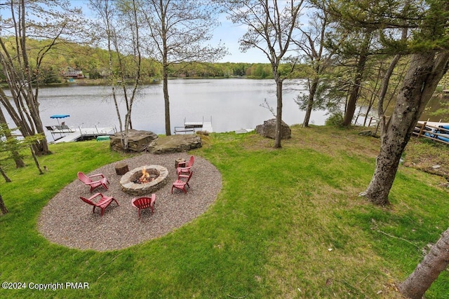 view of yard with an outdoor fire pit, a water view, and a boat dock