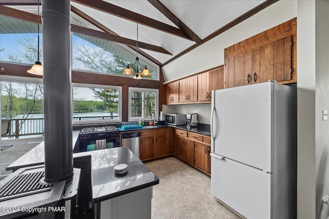 kitchen featuring a notable chandelier, dark countertops, appliances with stainless steel finishes, brown cabinetry, and a sink