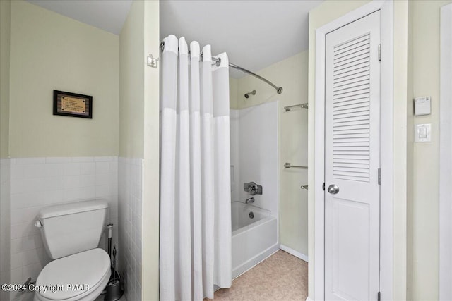 bathroom featuring a closet, tile walls, toilet, and shower / bath combo with shower curtain