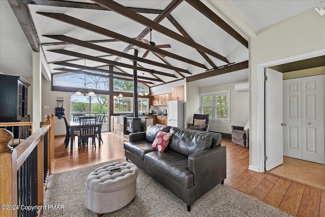 living area featuring beam ceiling, light wood finished floors, a wall mounted AC, high vaulted ceiling, and baseboards