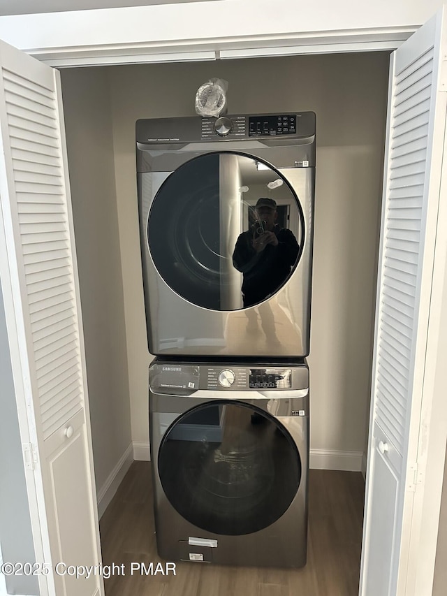 laundry room featuring stacked washer / drying machine and dark wood-type flooring