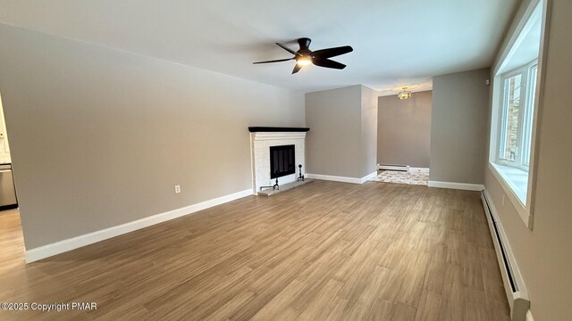 unfurnished living room featuring light hardwood / wood-style flooring, a fireplace, ceiling fan, and baseboard heating