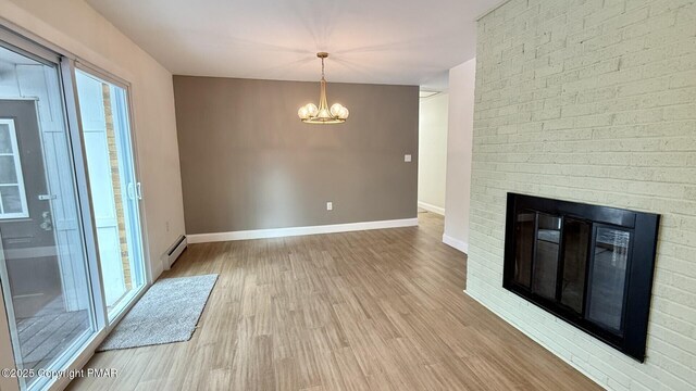 interior space featuring an inviting chandelier, light hardwood / wood-style floors, a brick fireplace, and a baseboard heating unit