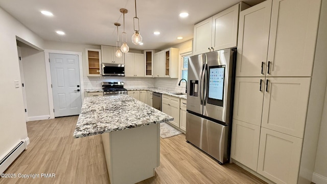 kitchen featuring appliances with stainless steel finishes, a baseboard heating unit, a center island, light stone countertops, and decorative light fixtures