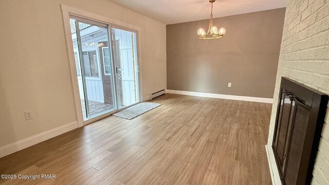 interior space with light wood-type flooring, an inviting chandelier, a fireplace, and baseboard heating