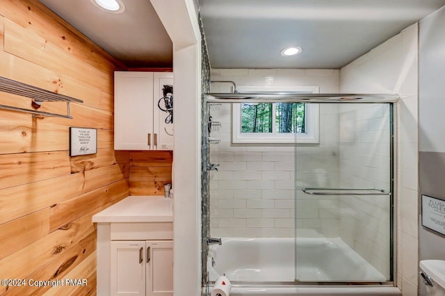 full bath with shower / bath combination with glass door, recessed lighting, toilet, and wooden walls