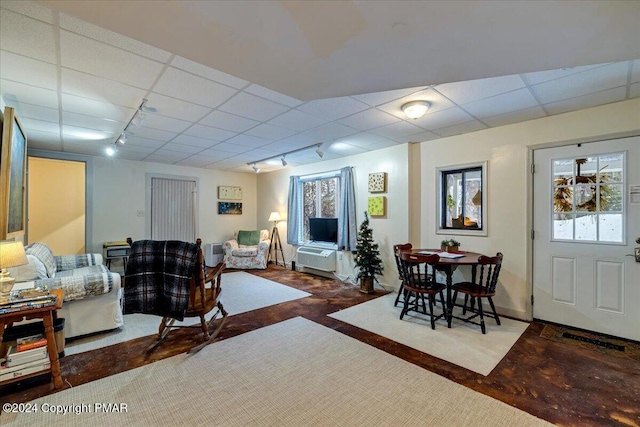 living room with a paneled ceiling, rail lighting, and concrete floors