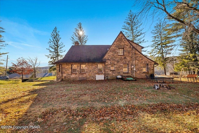 view of home's exterior featuring stone siding, a yard, and a chimney