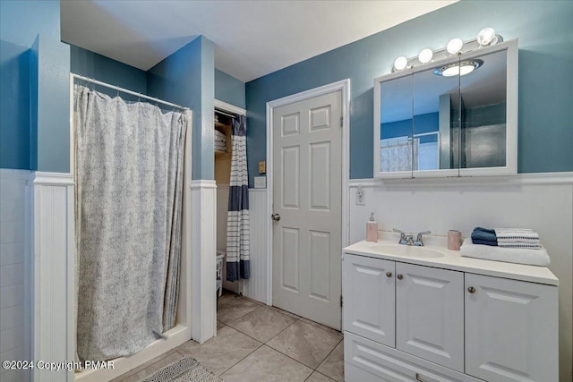 full bath with a shower with shower curtain, wainscoting, vanity, and tile patterned floors