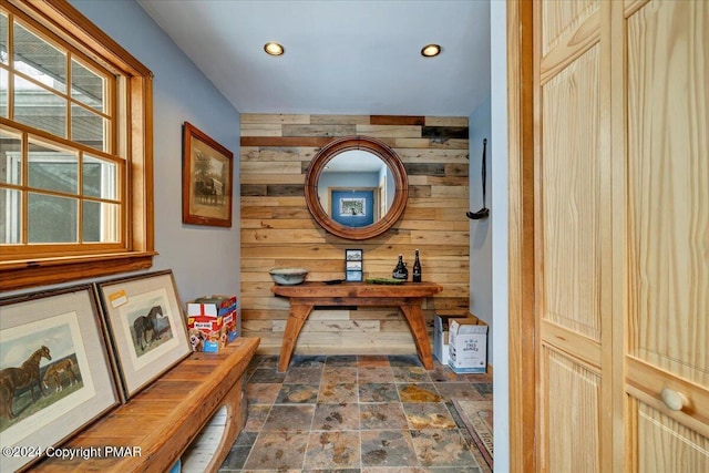 corridor with wood walls, stone finish floor, and recessed lighting