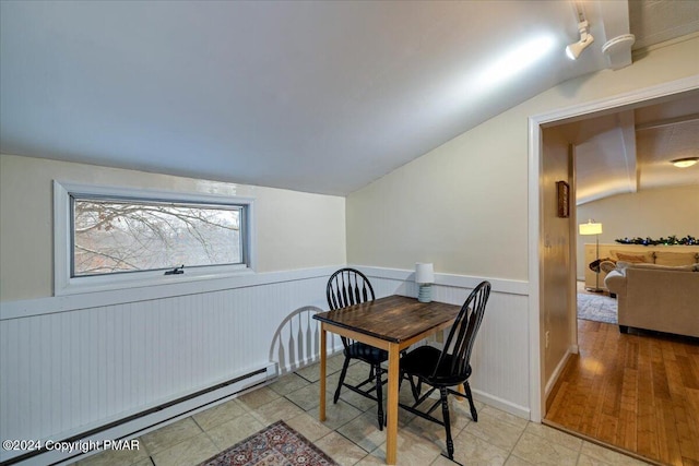 dining area featuring a wainscoted wall, a baseboard radiator, and lofted ceiling