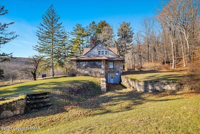 view of front of house featuring stone siding, a chimney, and a front yard