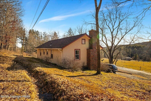 view of side of property featuring a chimney and stucco siding