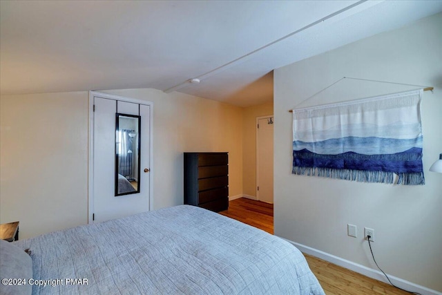 bedroom featuring vaulted ceiling, baseboards, and wood finished floors