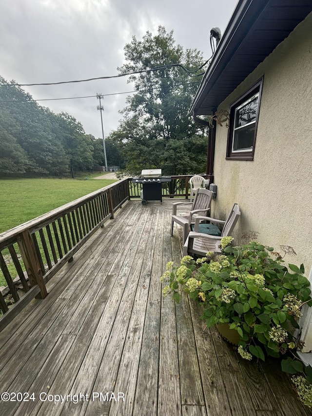 wooden terrace featuring a grill and a lawn